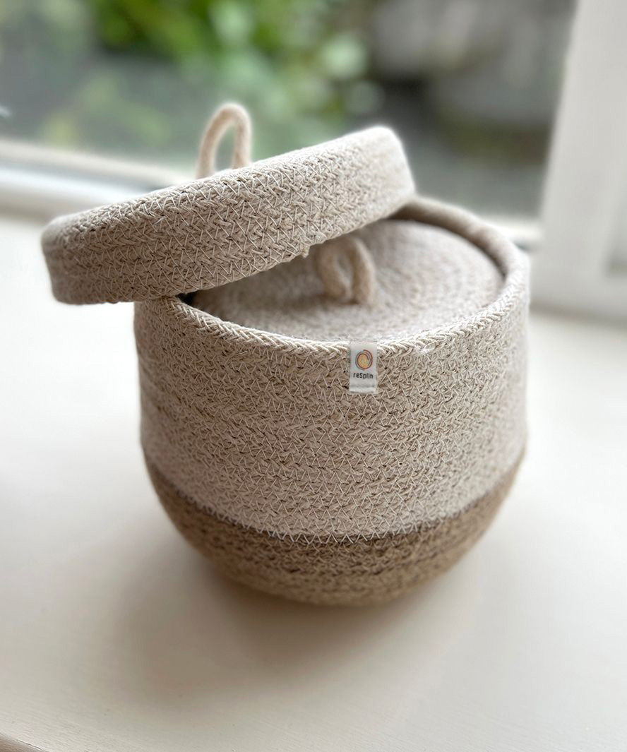 A close up of the Respiin natural jute lidded basket set showing the smallest basket inside the larger basket with the lid balancing on top.
