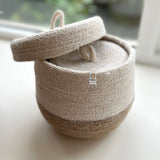 A close up of the Respiin natural jute lidded basket set showing the smallest basket inside the larger basket with the lid balancing on top.