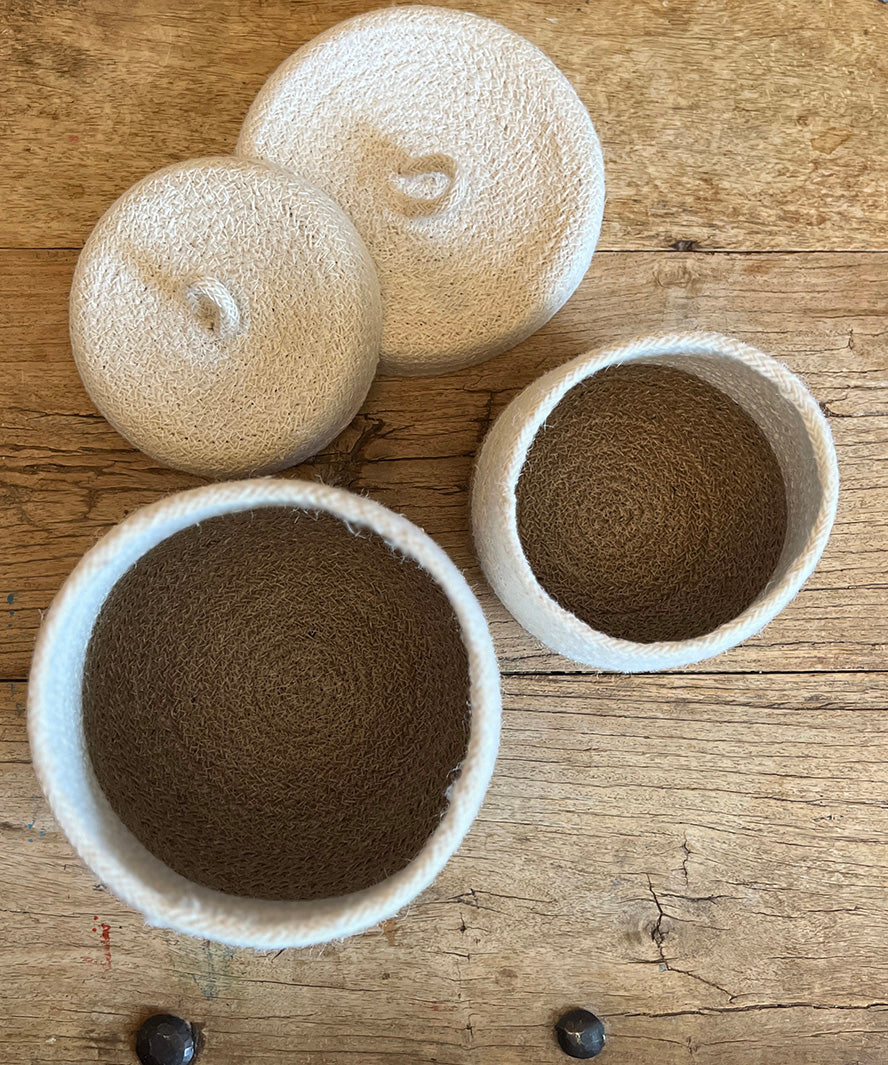 Top down view of the Respiin natural jute lidded basket set in white and natural showing standing upright on a wooden table showing the size difference.