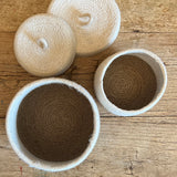 Top down view of the Respiin natural jute lidded basket set in white and natural showing standing upright on a wooden table showing the size difference.