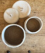 Top down view of the Respiin natural jute lidded basket set in white and natural showing standing upright on a wooden table showing the size difference.