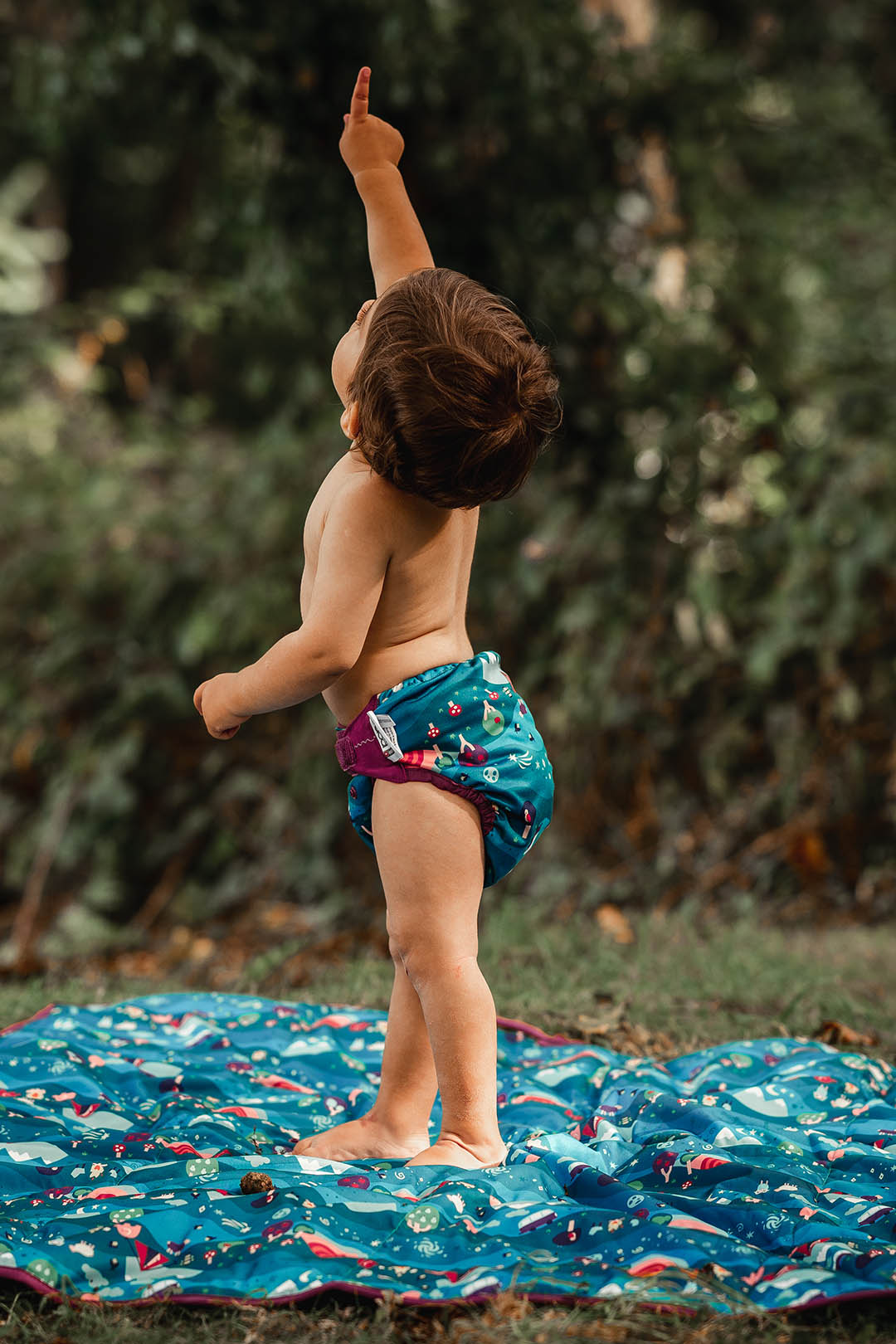 baby wearing reusable nappy and pointing upwards