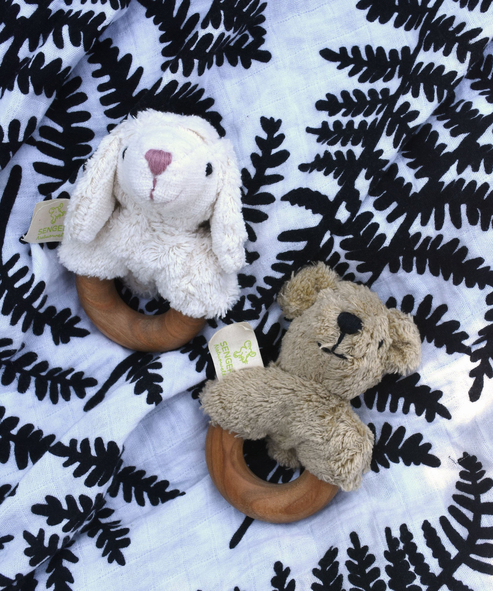 Senger bear and sheep baby grasping toys placed on an Etta Loves fern print sensory muslin cloth.