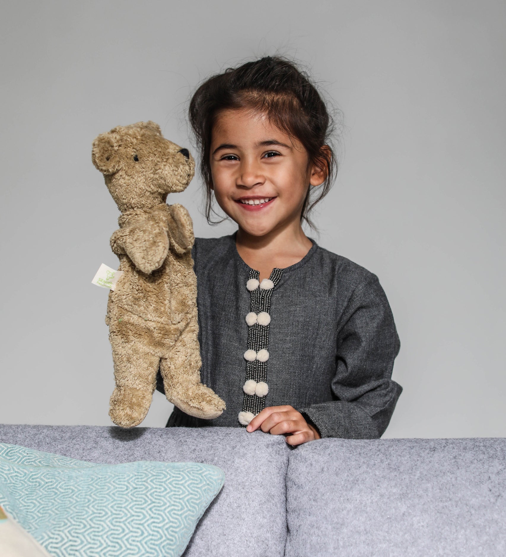 A child playing with a Senger beige bear Hand Puppet.
