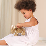 A child sitting down with a Senger beige Rabbit Bag on their lap. they are opening the zip of the bag.