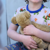 A close up of a small Senger beige cuddly teddy bear in a child's hands.