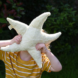 A child holding up a small Senger starfish cuddly toy in front of his face. The Senger soft toys are made from organic materials and natural fillings.