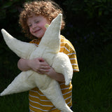 A child cuddling the large Senger starfish soft toy, the child's arms are wrapped around the starfish holding it close. The Senger starfish are part of a wide range of organic soft toys available here at babipur.