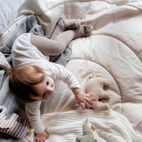 A child lying on a soft blanket and playing with the beige Senger elephant grasper available at Babipur.