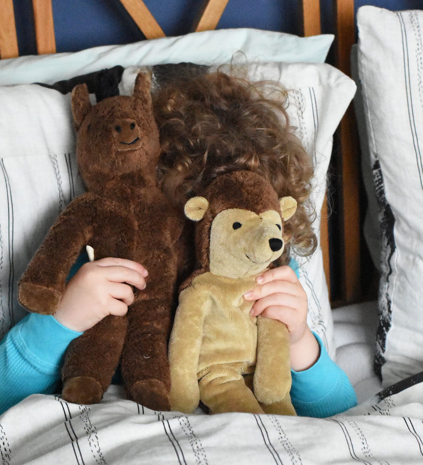 A child holding up a horse and hedgehog Senger floppy soft toys in front of their face whilst playing peekaboo with them. These toys are from the Senger Floppy collection, a range of soft toy animals made from organic and natural materials.