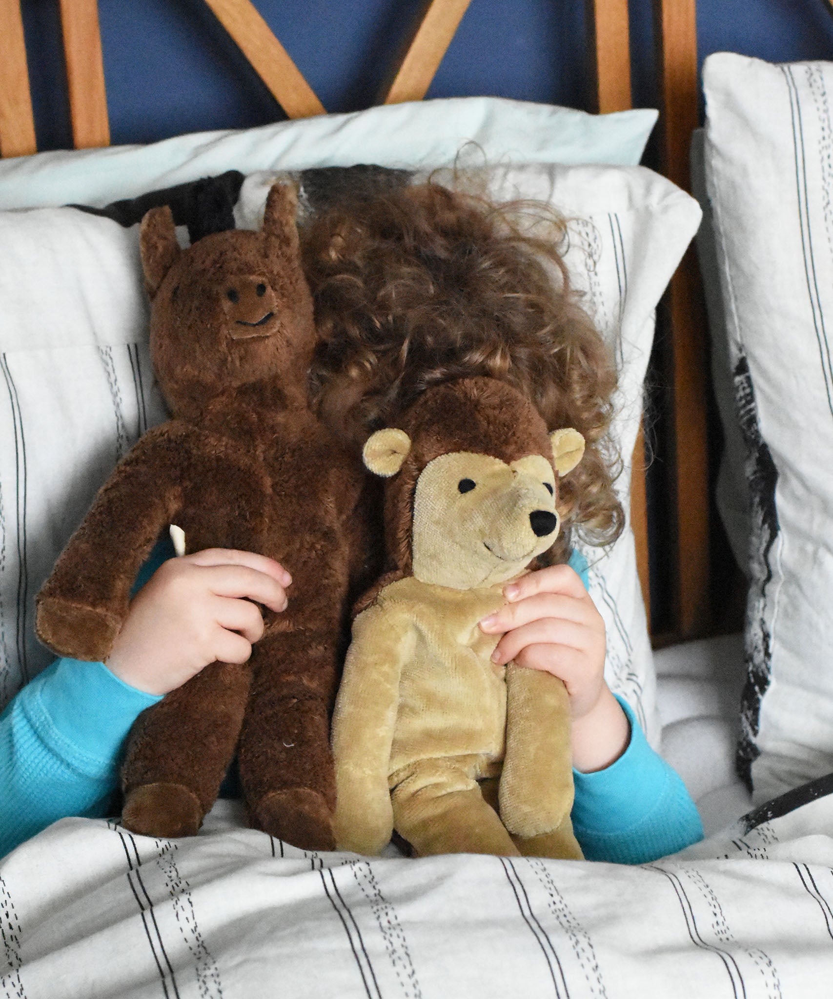 A child holding up a horse and hedgehog Senger floppy soft toys in front of their face whilst playing peekaboo with them. These toys are from the Senger Floppy collection, a range of soft toy animals made from organic and natural materials.
