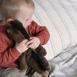 A close up of a child cuddling the Senger small brown floppy horse soft toy. This brown horse is from the Senger Floppy collection, a range of soft toy animals made from organic and natural materials.