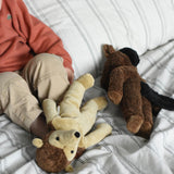 Two Senger soft toys placed on a cream and black striped duvet, a hedgehog and horse from Senger's floppy collection of soft toys made with organic cotton and natural fillings. A young child can be seen in the background.