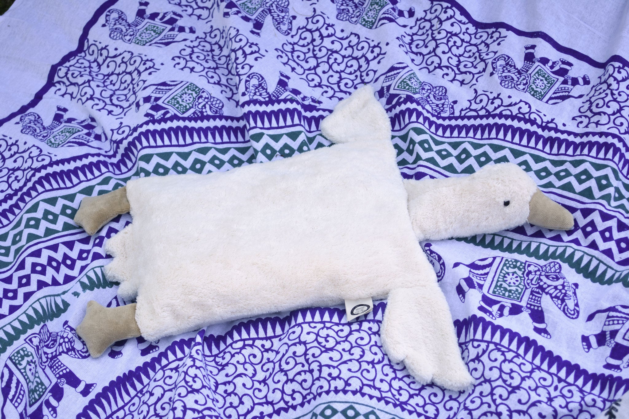 A Senger white organic cotton goose pillow placed on a blue and white patterned blanket.