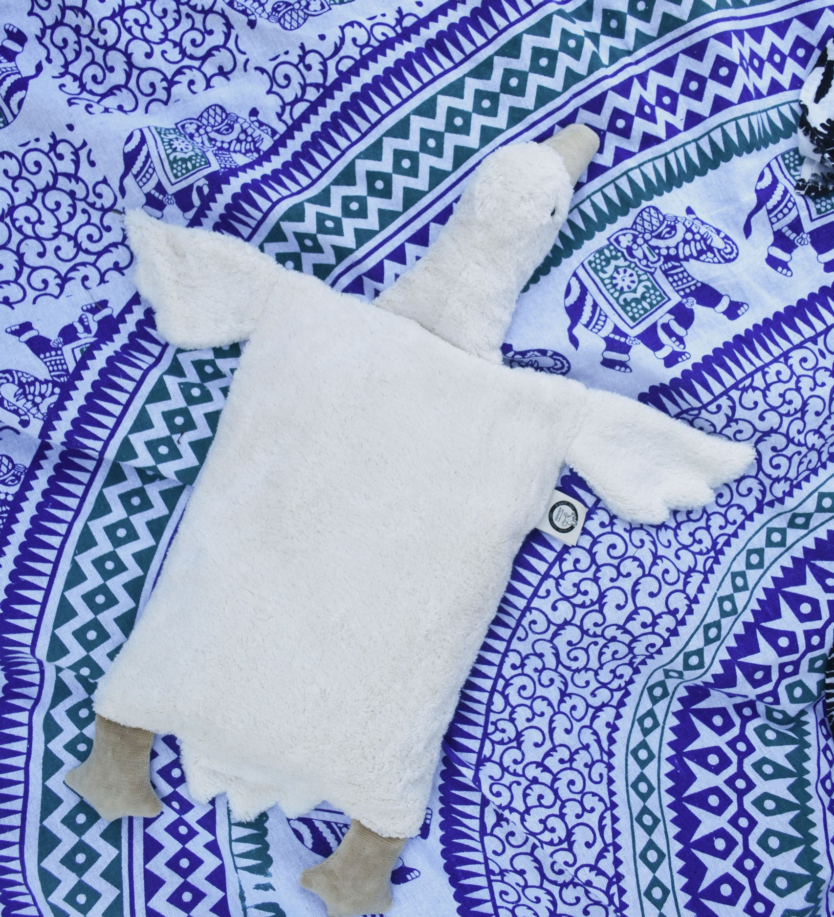 A Senger white organic cotton goose pillow placed on a blue and white patterned blanket.