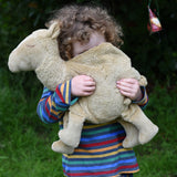 A child cuddling a large Senger Cuddly Camel Organic Heatable Soft Toy. The large camel soft toy is part of a wide selection of soft toys made from organic cotton and natural fillings available at Babipur.