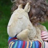 A close up of a child cuddling the large Senger Cuddly Camel Organic Heatable Soft Toy. The large camel soft toy is part of a wide selection of soft toys made from organic cotton and natural fillings available at Babipur.