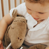 A toddler cuddling the organic cotton stuffed camel toy from Senger