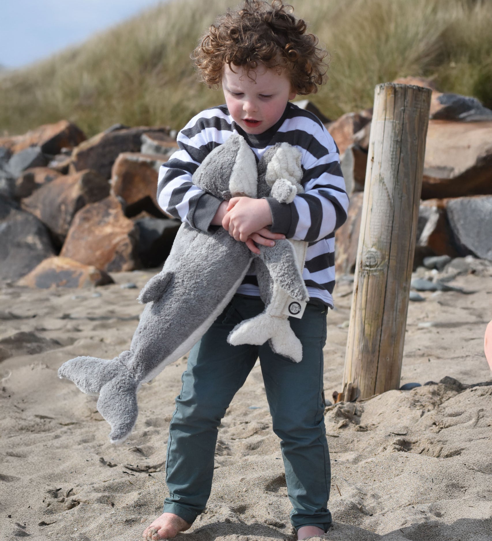 A child holding the large and small Senger cuddly whale animal soft toys with one in each arm.