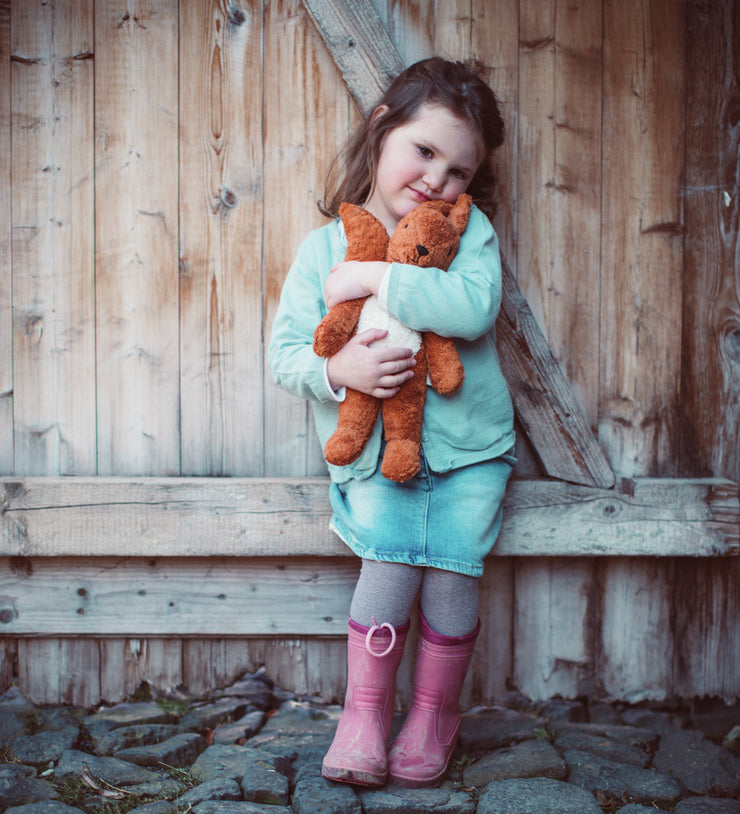 A little girl cuddling the Senger organic cotton small squirrel stuffed soft toy