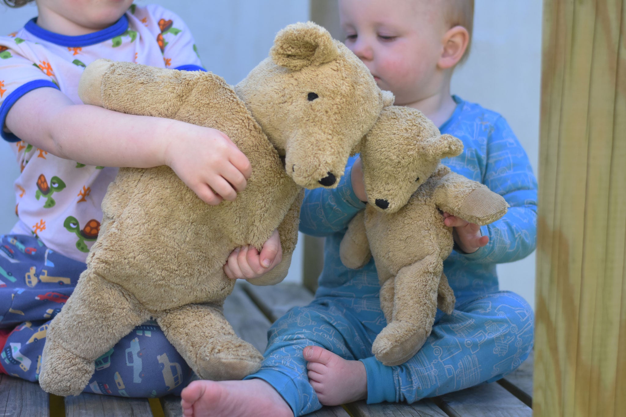 A close up of the large and small Senger beige cuddly bears in children's hands.