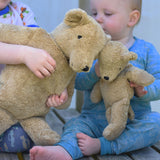 A close up of the large and small Senger beige cuddly bears in children's hands.