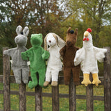 A collection of Senger hand puppets placed on a wooden fence. A donkey, frog, dog horse and chicken.