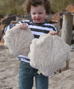 A child holding up a large and small Senger cuddly shell toy.