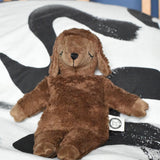 A Senger small brown cuddly sheep organic soft toy placed on a black and white monochrome patterned duvet. The small brown sheep is part of Senger's cuddly range of soft toys available at Babipur.