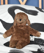 A Senger small brown cuddly sheep organic soft toy placed on a black and white monochrome patterned duvet. The small brown sheep is part of Senger's cuddly range of soft toys available at Babipur.