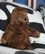 A Senger small brown cuddly sheep organic soft toy placed on a black and white monochrome patterned duvet. The small brown sheep is part of Senger's cuddly range of soft toys available at Babipur.