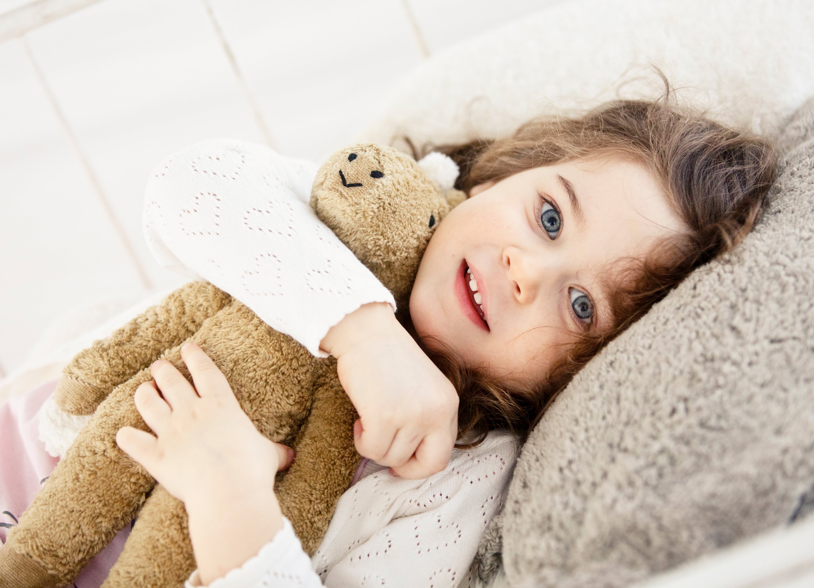A chlld laying down cuddling a Senger Small Floppy Horse.