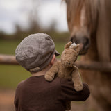 A child holding up  Senger Small Floppy Horse on their shoulder.