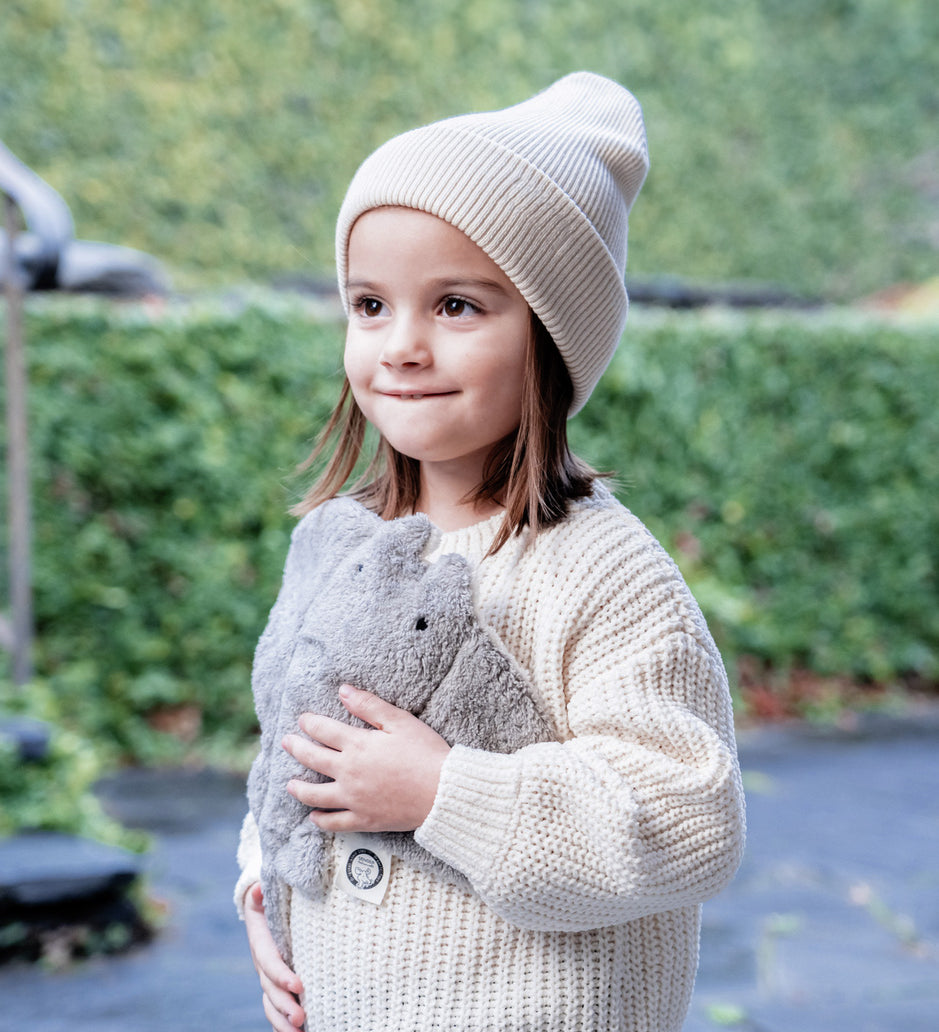 A little girl holding her Senger organic cotton heatable cuddly grey manta ray stuffed toy