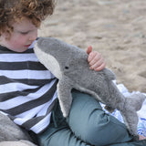 A child holding the small Senger whale cuddly animal up to their nose.