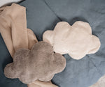 A white and grey cloud shaped Senger warming cushions placed on a bed.