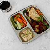A Slice Of Green Stainless Steel Divided Plate. The plate has hummus in the smallest section, carrot, cucumber and olives in the middle section and flatbread, salad and falafels in the biggest section. This stainless steel plate is suitable for snacks and meals and perfect for children and adults.