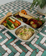 A Slice Of Green Stainless Steel Divided Plate. The plate has hummus in the smallest section, carrot, cucumber and olives in the middle section and flatbread, salad and falafels in the biggest section. This stainless steel plate is suitable for snacks and meals and perfect for children and adults.