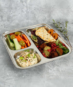 A Slice Of Green Stainless Steel Divided Plate. The plate has hummus in the smallest section, carrot, cucumber and olives in the middle section and flatbread, salad and falafels in the biggest section. This stainless steel plate is suitable for snacks and meals and perfect for children and adults.