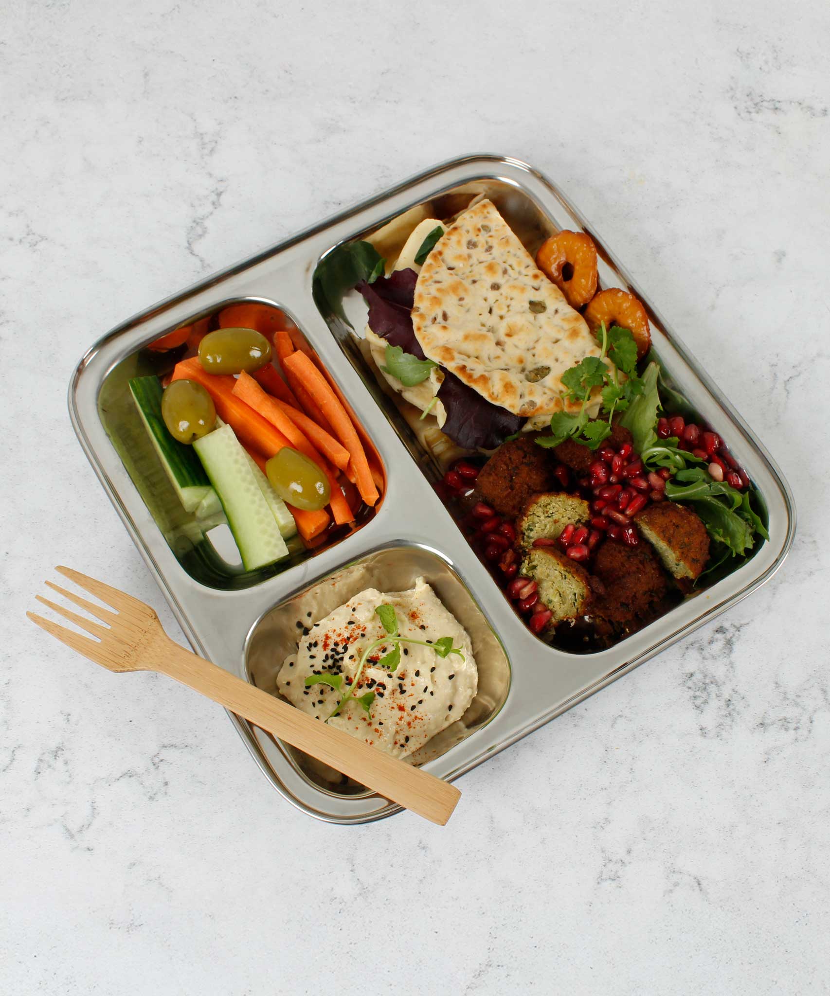 A Slice Of Green Stainless Steel Divided Plate. The plate has hummus in the smallest section, carrot, cucumber and olives in the middle section and flatbread, salad and falafels in the biggest section. This stainless steel plate is suitable for snacks and meals and perfect for children and adults.
