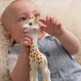 A baby happily grasping and chewing on the Sophie la Girafe® - Once Upon A Time 100% Natural Rubber Original Giraffe Teether