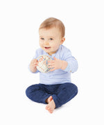 A baby playing with The Sophie the Giraffe natural Hevea rubber teething ball toy or babies, with non-toxic paints and textured elements.