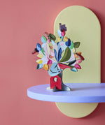 The Studio Roof 3D Pop Out Card Dream Tree on a purple shelf. A 3D cardboard DIY craft kit tree with different coloured leaves. This kit is part of a wide range of Studio Roof kits that are available at Babipur.