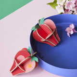 Studio Roof 3D Pop Out Card Strawberries placed on a blue tray. This 3D pop out card DIY kit is part of Studio Roof's fruits collection which is available at Babipur.