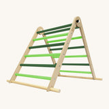 Triclimb folding wooden pikler climbing frame with light and dark green rungs. Features a natural coloured rungs on the bottom as a base.