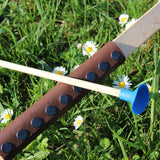A close up of the brown coloured leather look grip on the Vah Junior Wooden Bow. A blue tipped arrow can be seen alongside it.
