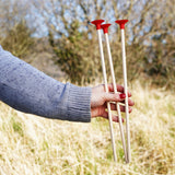 An adult holding up three red tipped safety arrows in their hand.