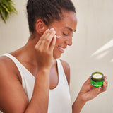 An image of a woman applying the Weleda Skin Food Nourishing Day Face Cream to their cheeks. This cream is available at Babipur.