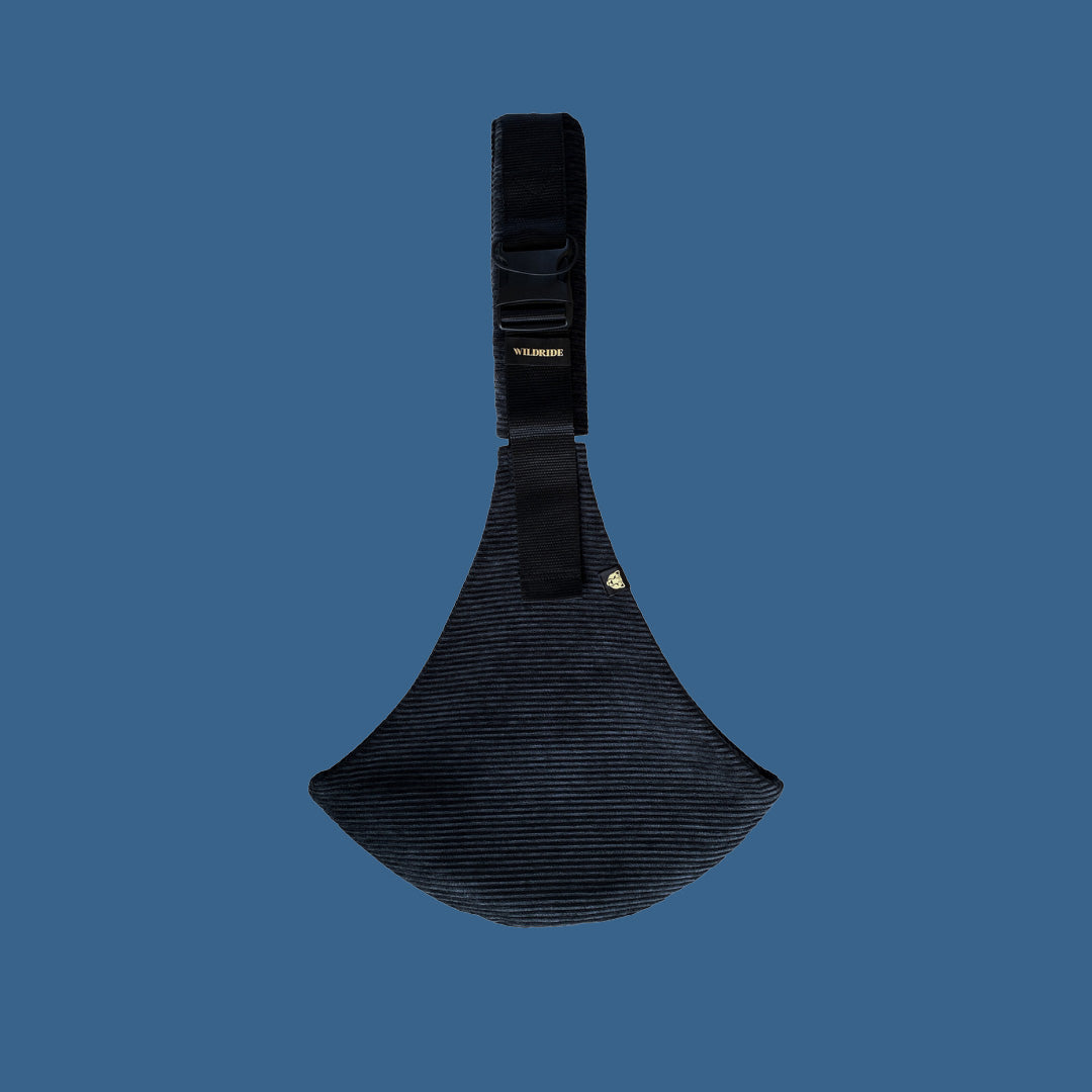 The black corduroy Wildride toddler carrier sling, on a blue background.