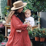 A woman carrying her baby with the Wildride stylish hip sling carrier for toddlers, in a Boho print